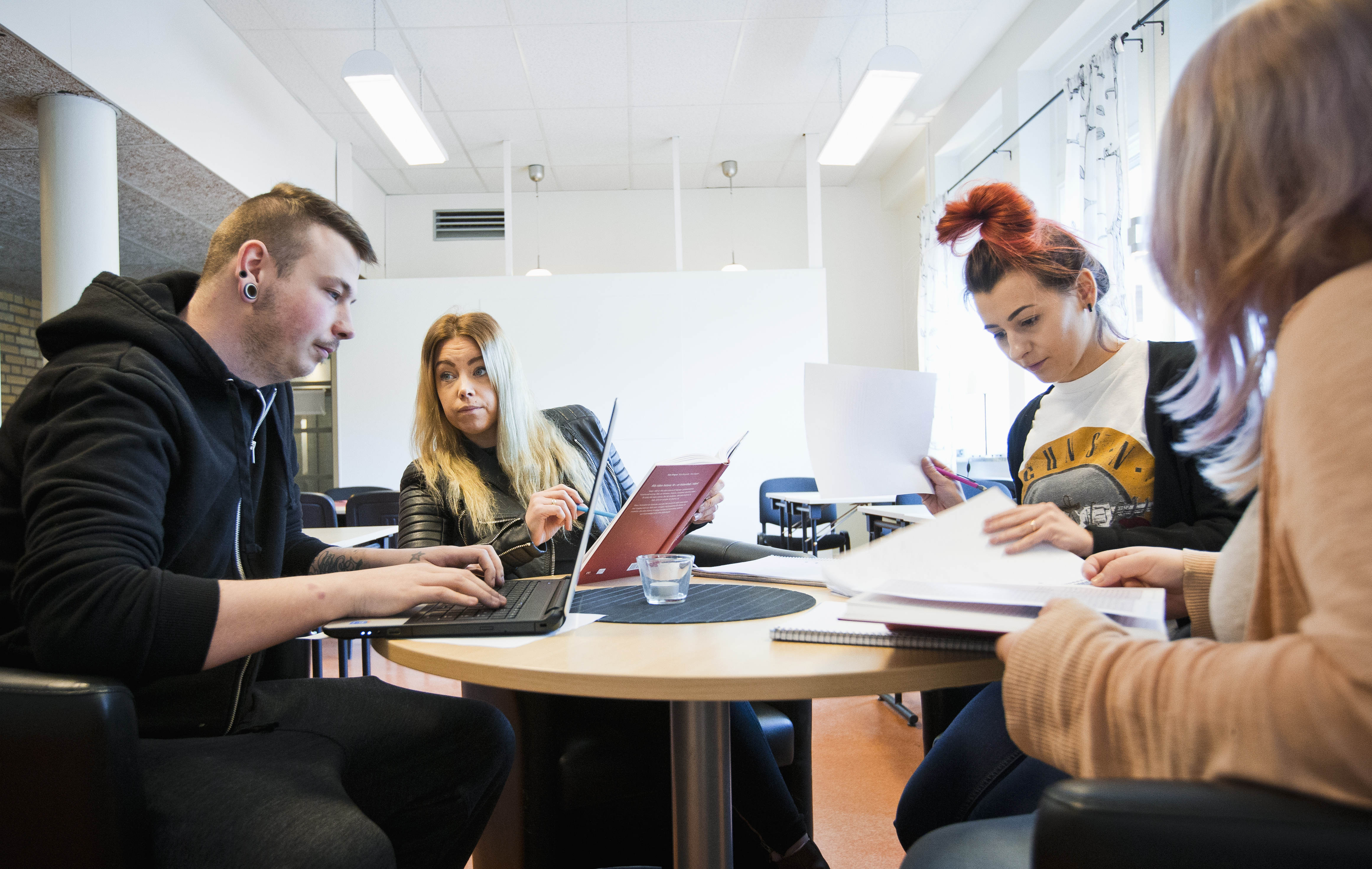 Elever på Klarälvdalens folkhögskola studerar tillsammans vid ett runt bord.